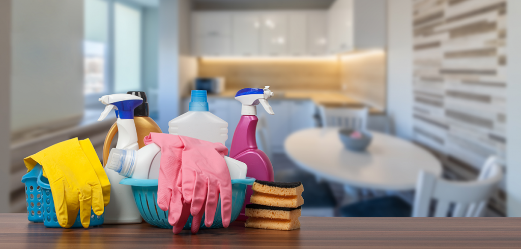 an array of cleaning products, sponges and rubber gloves are sitting on a kitchen worktop 